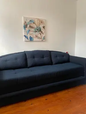 a blue couch in a living room with a painting at 5min Airport in Surčin