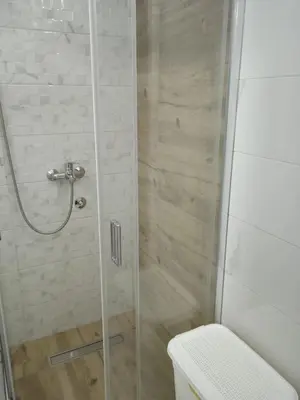 a shower with a glass door next to a toilet at Happy Day in Obrenovac