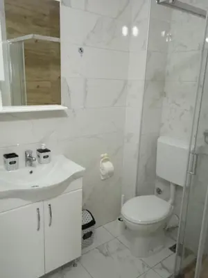 a white bathroom with a toilet and a sink at Happy Day in Obrenovac