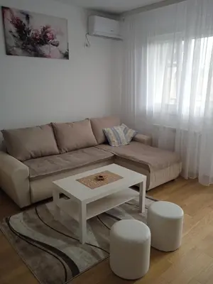 a living room with a couch and a table and two stools at Happy Day in Obrenovac
