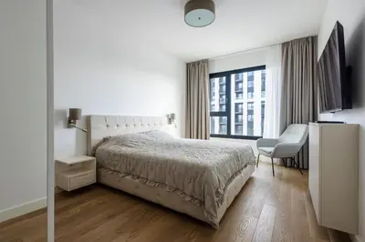 a white bedroom with a bed and a chair at Terra Luxe Residences in Sajmište