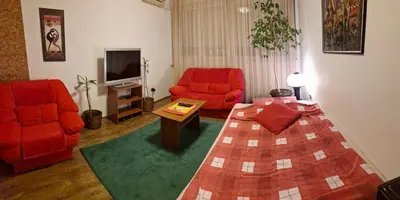 a living room with a bed and two red chairs at NeraBella Apartment in Belgrade