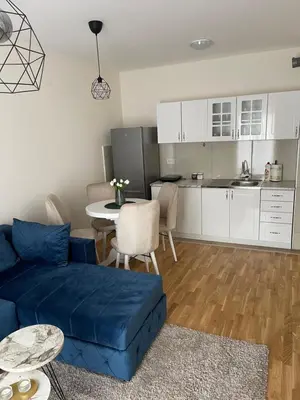 a living room with a blue couch and a kitchen at Cvetanov trg LUX 2 in Belgrade