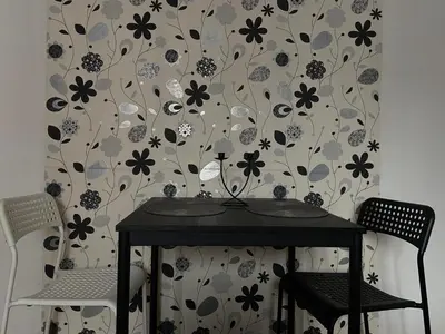a table with two chairs in front of a floral wallpaper at Mala Bella in Zemun