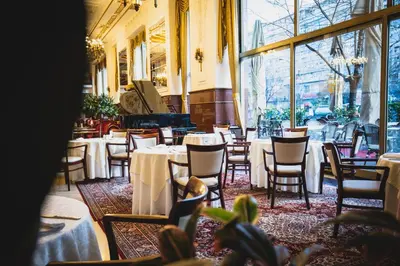 a restaurant with tables and chairs and a piano at Hotel Moskva in Belgrade