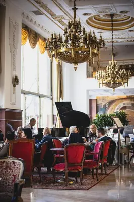 a group of people sitting at a table with a piano at Hotel Moskva in Belgrade