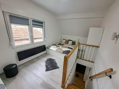a small bedroom with a bed and a window at Mini duplex apartman in Dušanovac (historical)