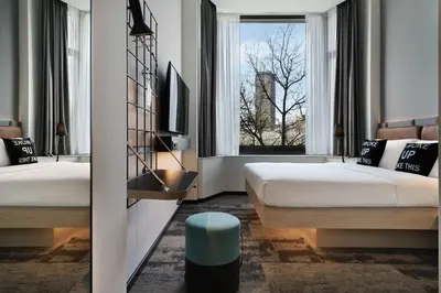 a hotel room with two beds and a window at Moxy Belgrade in Belgrade
