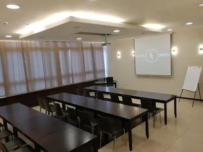 a conference room with black tables and chairs and a screen at Hotel Srbija-FREE PARKING in Belgrade