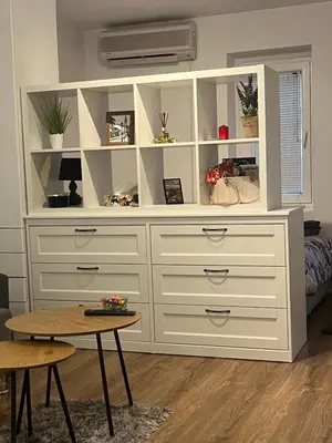 a large white dresser in a room with a table at Bellissima Apartment in Belgrade