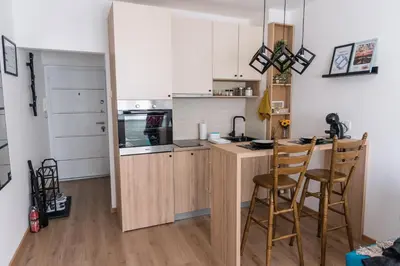 a kitchen with white cabinets and a counter with stools at Cube23 in Belgrade