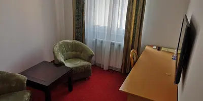 a living room with a green chair and a table at Hotel Elegance in Belgrade