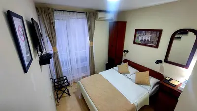 a bedroom with a bed and a mirror and a window at Hotel Villa Panorama in Belgrade