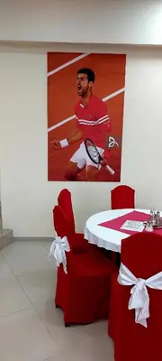 a table and chairs with a poster of a tennis player at Hotel Villa Panorama in Belgrade