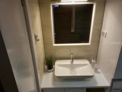a white sink in a small bathroom with a mirror at LL65 Apartmens Airport Nikola Tesla in Ledine