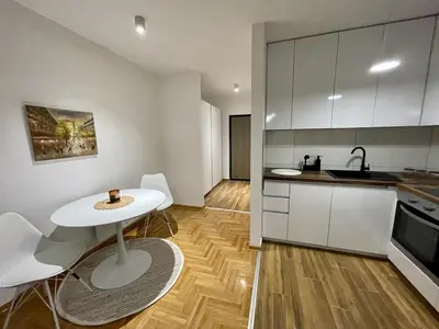 a kitchen with a white table and white cabinets at LL65 Apartmens Airport Nikola Tesla in Ledine