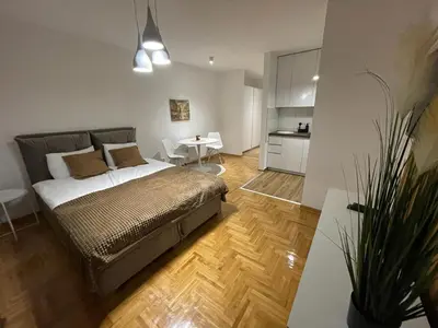 a bedroom with a bed and a table and a kitchen at LL65 Apartmens Airport Nikola Tesla in Ledine