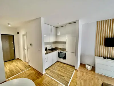 a kitchen with white cabinets and a wooden floor at LL65 Apartmens Airport Nikola Tesla in Ledine