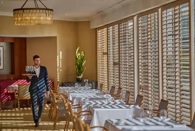 a man walking through a dining room with tables at Hyatt Regency Belgrade in Belgrade