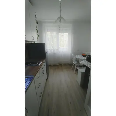a kitchen with white cabinets and a wooden floor at Kennedy apartment in Tošin Bunar