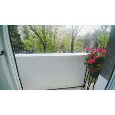 a window with a view of a balcony with flowers at Kennedy apartment in Tošin Bunar
