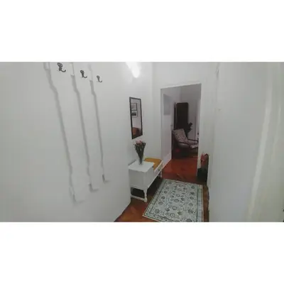 a hallway with a white room with a table and a rug at Kennedy apartment in Tošin Bunar