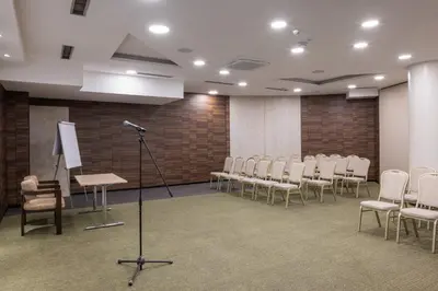 a conference room with white chairs and a microphone at Nobel Design Hotel in Belgrade
