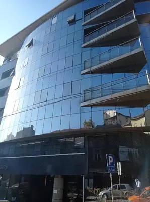 a tall glass building with a parking sign in front of it at Nobel Design Hotel in Belgrade