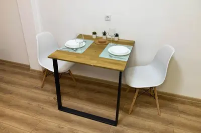 a wooden table with two white chairs and plates on it at Cozy & fully equipped studio in the heart of downtown and next to Kalemegdan in Belgrade