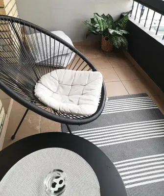a rattan chair with a pillow sitting on a floor at Apartman Darvin / Lux in Belgrade