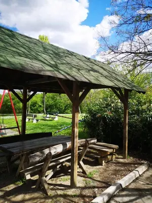 a wooden picnic shelter with benches in a park at Apartman Darvin / Lux in Belgrade