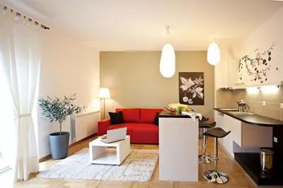 a living room with a red couch and a kitchen at Boutique Apartments 360º in Belgrade