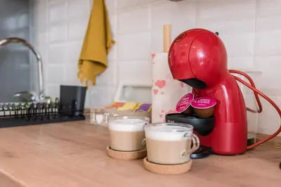 a red mixer sitting on a kitchen counter with two cups of coffee at Apartman Mila23 in Rospi Ćuprija