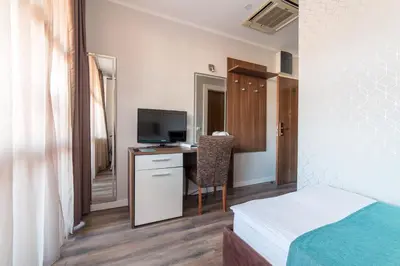 a bedroom with a bed and a desk with a television at Balkan Hotel Garni in Belgrade