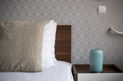 a bedroom with a bed with a blue vase on a table at Balkan Hotel Garni in Belgrade