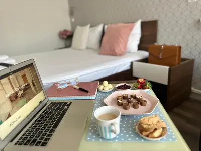 a desk with a laptop and a plate of cookies and a cup of coffee at Balkan Hotel Garni in Belgrade