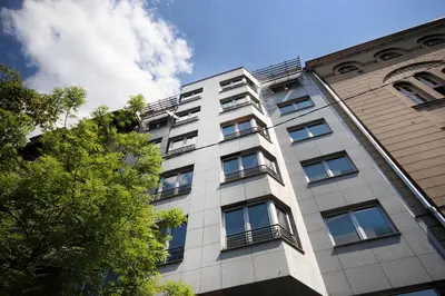 a tall white building with windows and a tree at Apartments Belgrade in Belgrade