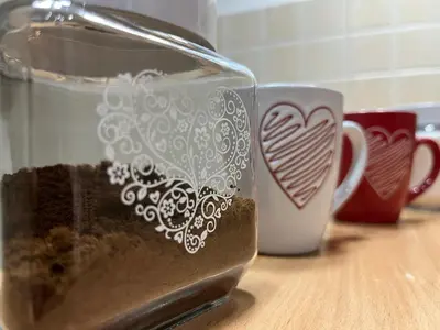 a glass jar with a heart on it next to two cups at Dalmatinska Apartman in Belgrade