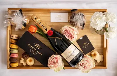 a wooden tray with a bottle of wine and flowers at Hotel Royal Inn in Belgrade