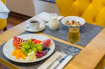 a table with a plate of fruit and a glass of milk at Hotel Royal Inn in Belgrade