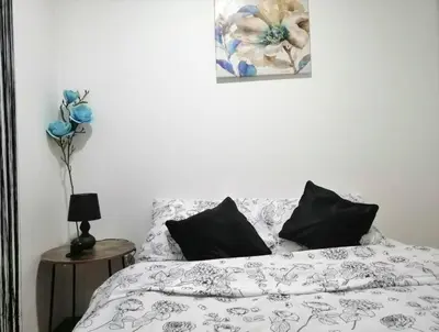 a bed with black and white sheets and a vase of flowers at MB apartman in Obrenovac