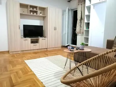 a living room with a table and chairs and a television at MB apartman in Obrenovac