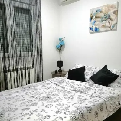 a bedroom with a bed with a white comforter and a window at MB apartman in Obrenovac