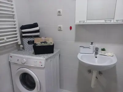 a white bathroom with a washing machine and a sink at MB apartman in Obrenovac
