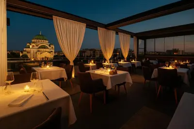 a restaurant with white tables and chairs and a building at CRYSTAL Hotel Belgrade in Belgrade