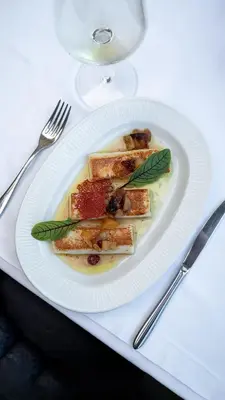 a white plate with food on a table with a glass at CRYSTAL Hotel Belgrade in Belgrade