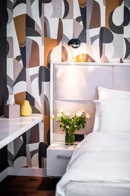 a bedroom with a bed and a vase of flowers on a night stand at CRYSTAL Hotel Belgrade in Belgrade