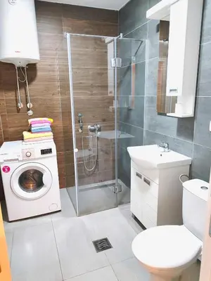 a bathroom with a shower and a washing machine at Lux apartman Ub in Ub