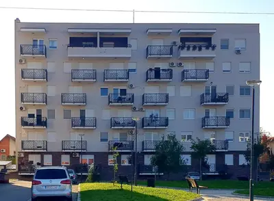 a building with balconies and a car parked in front of it at Lux apartman Ub in Ub