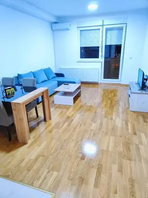 a living room with a blue couch and a table at Lux apartman Ub in Ub